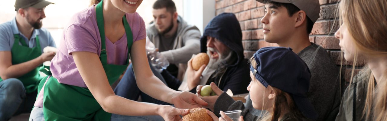 Volunteers giving food to poor people indoors